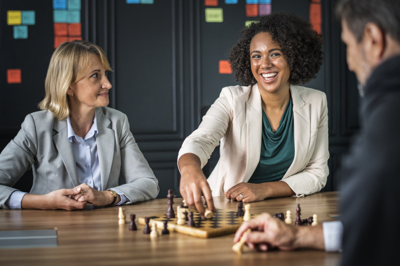 楼内男女下棋|人,典当,团体,国王,国际象棋,坐,多元文化,女人,娱乐,室内,成人,手,朋友,木制,桌子,棋子,棋盘,棋盘游戏,游戏,男人,白人,皇后,象棋车,金发,面部表情,骑士,黑白-海量高质量免版权图片素材-设计师素材-摄影图片-mitapix-美塔图像