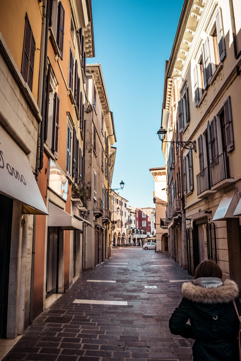 大衣的妇女站立在大厦之间Woman in Parka Stands in Between Buildings-Alley,ancient,Architecture,buildings,cobblestone street,Daylight,downtown,narrow,outdoors,pavement,person,shops,square,Street,tourism,Town,Travel,Urban,windows,人,古老,商店,大厦,建筑学,户外,旅游业,旅行,正方形,狭窄,白天,窗口,胡同,街市,街道,路面,都市,镇,鹅卵石街道-海量高质量免版权图片素材-设计师素材-摄影图片-mitapix-美塔图像