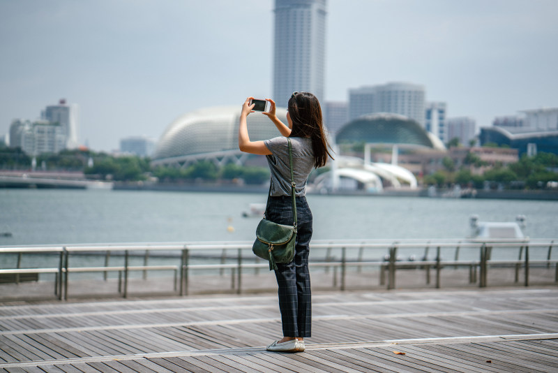 站着拍照的女人|iPhone,人,城市,城市景观,女士,女孩,女性,屏幕,建筑,建筑物,户外,手,手机,技术,拍照,数字,无线,景观,智能手机,木板路,模糊背景,水,海湾,游客,电话,白天,移动电话,站立,触摸屏-海量高质量免版权图片素材-设计师素材-摄影图片-mitapix-美塔图像