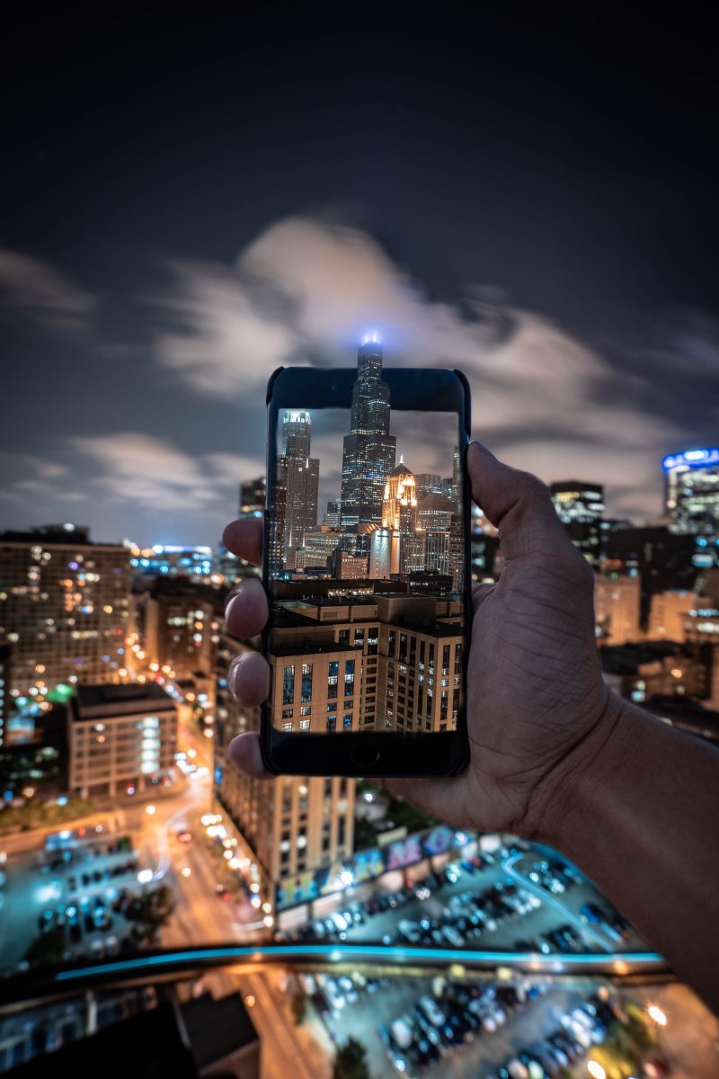 人在摩天大楼的照片Person Taking Photo of Skyscraper|业务,体系结构,在户外,城市,城市景观,塔,天际线,建筑,摩天大楼,无人机视频,晚上,晚上的时间,灯,照亮,街-海量高质量免版权图片素材-设计师素材-摄影图片-mitapix-美塔图像