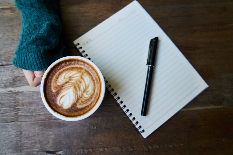 在拿铁咖啡杯旁边的黑色钢笔Black Pen on Ruled Paper Beside Cup of Latte|Brown,Café,caffeine,closeup,coffee,coffee cup,cup,cup of coffee,Desk,foam,Hand,indoors,latte,latte art,liquid,notebook,paper,pen,table,wood,wooden,咖啡,咖啡因,咖啡杯,咖啡馆,在室内,手,拿铁咖啡,拿铁艺术,木,木材,杯咖啡,杯子,桌子,棕色,泡沫,液体,特写,笔,笔记本,纸,表-海量高质量免版权图片素材-设计师素材-摄影图片-mitapix-美塔图像