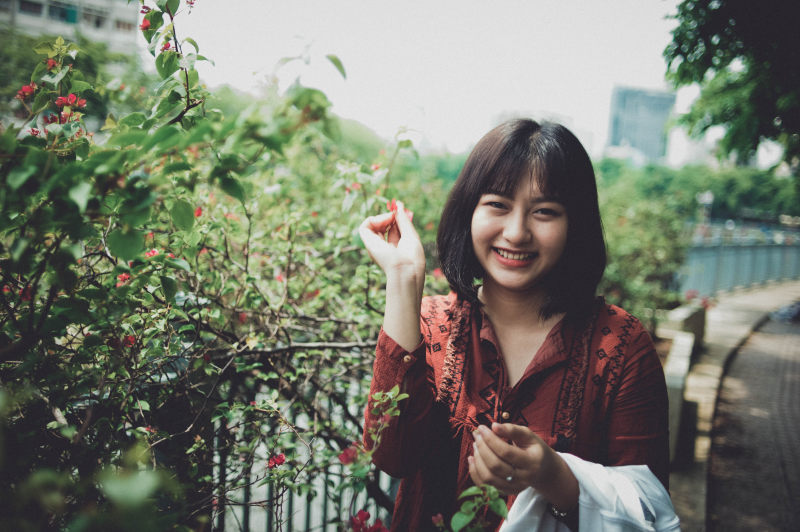 站在植物旁边穿着红领衬衫的女人|人,可爱,女人,女孩,微笑,肖像-海量高质量免版权图片素材-设计师素材-摄影图片-mitapix-美塔图像